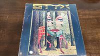 Front cover of Styx The Grand Illusion vinyl album showing surreal forest and face artwork