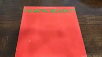 Front cover of the Talking Heads :77 album showing red background with green text.