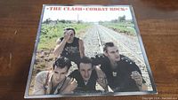 Front cover of vinyl LP Combat Rock showing band members sitting by train tracks.