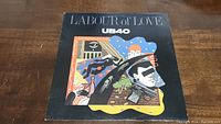 Front cover of UB40 Labour Of Love vinyl album showing colorful abstract illustrations on a black background.
