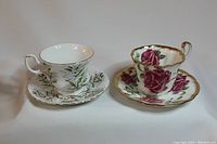 Both teacup and saucer sets shown side by side, displaying the floral patterns and gold trim.
