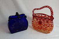 Two art glass purses together, showing the size and color contrast between the blue and red-white swirled pieces