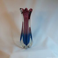 Art glass vase with blue and fuchsia colors shown against plain background from front angle.