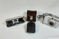 Carl Zeiss Jena Opera lenses, brown leather case, and black viewfinder device photographed together on white background