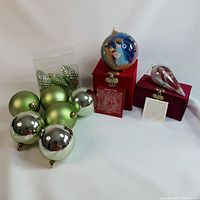 Festive Christmas ornaments including metallic green and silver balls, a painted snowman ball, and two boxed Le Bien hand-painted glass ornaments