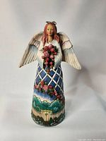 Front view of the Jim Shore Guardian Of The Garden And Flowers figurine showing the angel's face, bouquet, detailed dress, and wings.