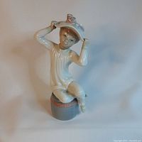 Front view of the Lladro porcelain figurine showing the girl seated on the pouf holding her hat