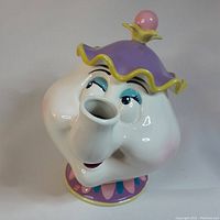 Front close-up of Mrs. Potts musical teapot figurine showing face and lid features.