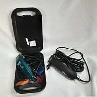 Blue Wahl clipper inside a black plastic carrying case with multiple colored comb attachments and blade oil bottle visible.