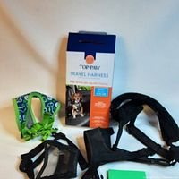 Photo of all items including travel harness box, green harness, black muzzles, and black pouch