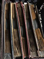 Five cardboard holders vertically holding multiple 78 RPM records seen from the top, some sleeves bent and aged.