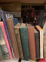 Shelf with a variety of antique and vintage books including titles like 'Batman Two-Face vs Batman' and 'The Tolkien Reader.' Includes records and music sheets.