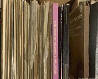 Various vinyl records and CDs in a collection of classical music with visible titles like 'The Best of Gilbert & Sullivan' and 'Karajan Conducts Favorite Tchaikovsky.' The records show wear indicating use and age.