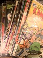 Photo showing a stack of comic books in plastic protective sleeves, including Kamandi and other titles