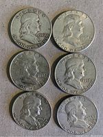 Obverse side of six Franklin half dollar coins showing profile of Benjamin Franklin with dates 1949, 1952, 1938, 1953, 1952D, and 1962D