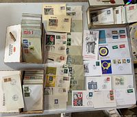 Top view of multiple postmarked envelopes and postcards spread on table and inside boxes. Various stamps and postmarks visible, mostly Germany Berlin.