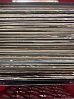 Photo showing a stacked collection of vinyl record albums in sleeves, edges showing wear consistent with lightly used vinyl.
