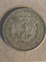 Reverse side of 1883 Morgan Silver Dollar showing eagle with arrows and olive branch and inscriptions.