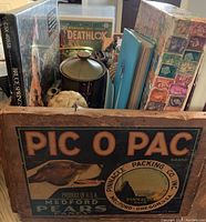 Wooden Pic O Pac box labeled with a dog's image filled with various items including books, pottery, and collectibles.