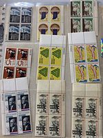 Photo showing various blocks of 4 stamps including Benjamin Franklin, Indiana, historical architecture, and cartoon figure stamps.
