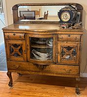 Front three-quarter view of the antique tiger oak sideboard showing mirrored back, center display cabinet, side doors and drawers