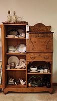 Full view of wooden cabinet filled with mismatched china, figurines, bowls, plates, and other decorative items.