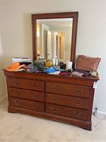 Overall view of wooden dresser with various items arranged on top, showing attached mirror and room background.