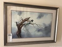 Full view of one signed framed art print depicting a bird on a leafless tree branch against a cloudy background.