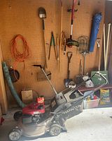Honda push mower below pegboard with assorted tools
