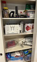 Overview of three shelf storage with kitchen appliances and office supplies