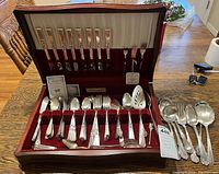 Original mahogany chest containing compartments with various Oneida Community flatware pieces including forks, spoons and serving utensils.