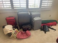 View of the entire lot showing all suitcases, bags and cases arranged on a beige carpet under white plantation shutters.