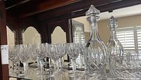 Waterford crystal stem glasses and decanters displayed on glass shelf with mirror background