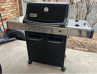 Full view of grill under covered patio showing hood, side shelves and lower cabinet