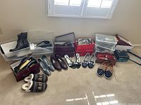 Full lot of various women's shoes and slippers displayed on carpet floor next to window. Includes boots, sneakers, loafers, moccasins, sandals, slippers mostly size 10.