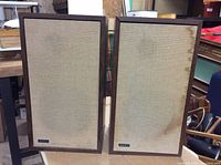Front view of the pair of Advent speakers, showing the beige fabric grills with noticeable stains and the dark wooden frames.