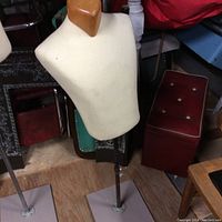 View of two male torso display mannequins on homemade adjustable metal stands with wooden neck toppers.