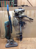 Boat motor mounted on a cardboard background next to the industrial vacuum