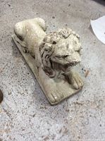 Overall angled front-left view showing lion lying on base with visible wear and dirt.