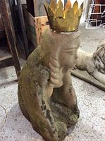 Concrete princess statue with a gold metal crown on head, showing side profile with moss and wear on concrete surface.
