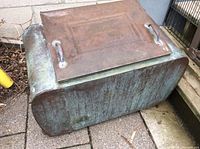 Side view of rectangular copper vat showing green oxidation patina and attached metal handles on flat lid.