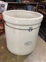Full view of the cream colored Medalta 5 gallon crock with metal wire handle and blue number 5 marking.