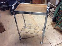 Full view of the mid-century cart showing chrome frame, wood top, and wire lower shelf with casters.