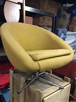 Front three-quarter view of mustard yellow bucket chair showing curved shell and cushion