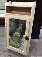 Front view of the vintage wooden washroom wall vanity cabinet showing the mirrored door with a metal latch and an open shelf above.