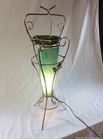 Front view of the green glass floor lamp with metal frame and illuminated base showing the integrated ashtray.