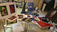 Overview of multiple matted and unmatted photos including colorful abstract shots and architectural images on tables and easels