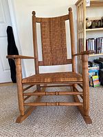 Front view of vintage Carolina Rocker showing detailed woven seat and back with wooden armrests and turned legs.