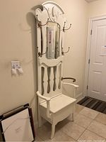 Front view of white shabby chic hall tree bench with mirror, hooks, and umbrella holder, situated in an entryway.