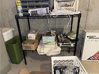 First shelving unit with various household items including boxes, cloths, and a small plastic bin.